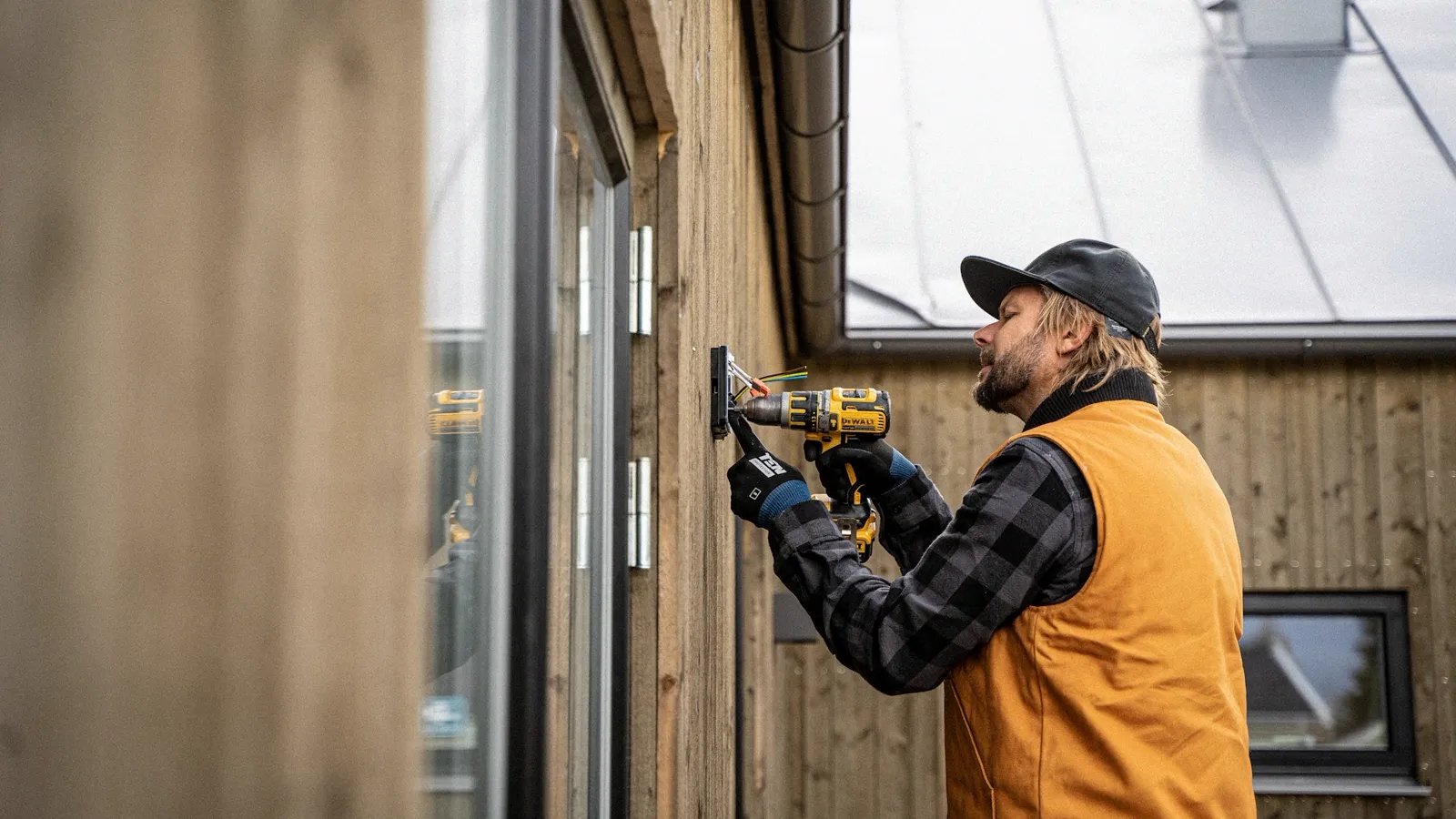 A tradesman fitting a window frame with a cordless drill